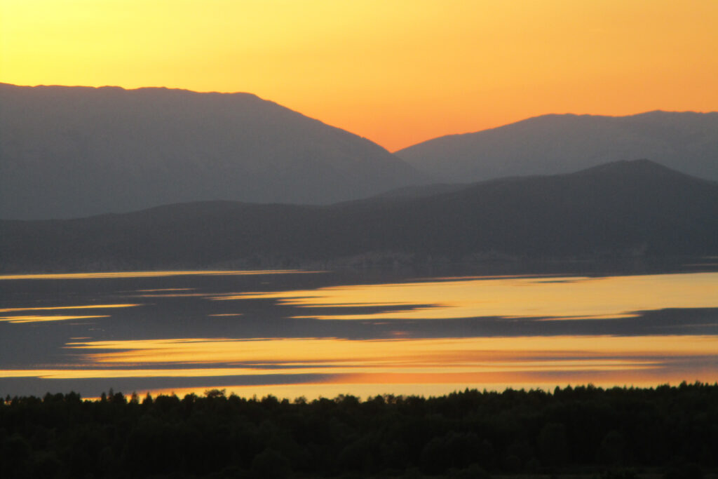 Sunset over Great Prespa Lake at the point where the borders of Greece, Albania, and the Republic of North Macedonia meet. Photo by Loring Danforth.